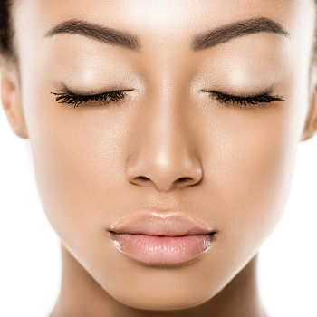Close-up of a person with closed eyes and neutral expression, showing smooth, even-toned skin and well-groomed eyebrows.