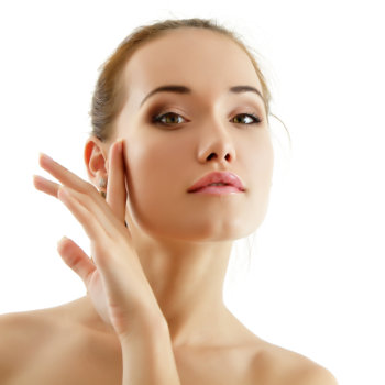 A woman with a neutral expression gently touches her face with her hand against a white background.